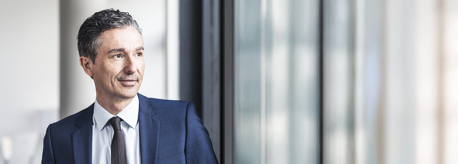 Businessman looking confidently out the window – partnership and growth through professional distribution services.